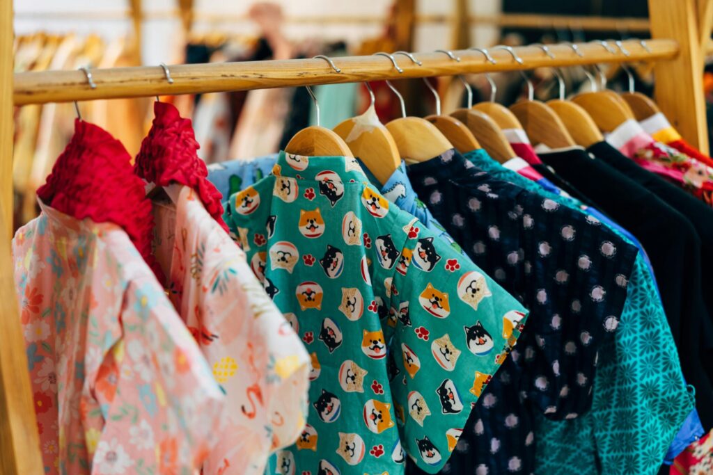 Vibrant clothes hanging on a wooden rack in a boutique shop.